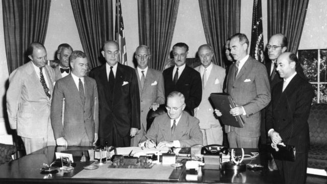 President Harry S. Truman signing the North Atlantic Treaty, marking the beginning of NATO, in 1949