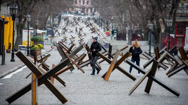 People walking in the street among dozens of anti-tank weapons.