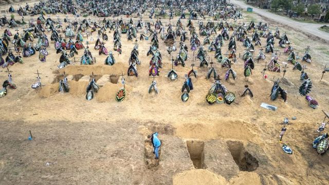 A gravedigger prepares the ground for a funeral at a cemetery in Irpin, Ukraine. The first several rows contain people killed during the Russian occupation of the area.