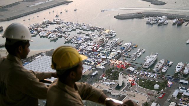 Indian workers watch the openning of Dubai's international boat show from the 50th floor of the tower which is beign constructed behind the Dubai International Marine Club, 14 March 2006.
