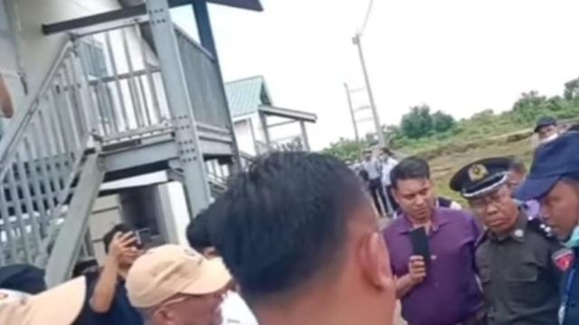 Rohingya refugees standing next to Myanmar officials