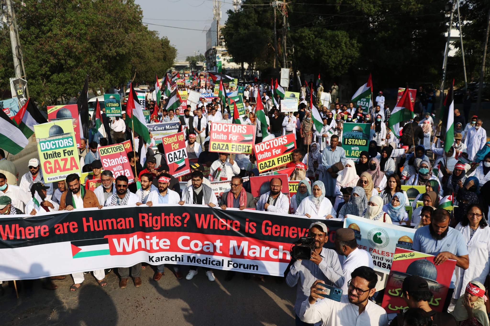 May be an image of 1 person, crowd and text that says "STAND COAT ARCH upi DOCTORS Unite For GAZA KarhMedic DOCTORS Stands GAZA DOCTORS Unite For GAZA FIGHT Unite DOCTORS GAZA Fo FIGH ISTAND AO Where are Human Rights? Where iS Genev: White Coat March Karachi Medical Forum ALES لبيكياقصى AQSA"